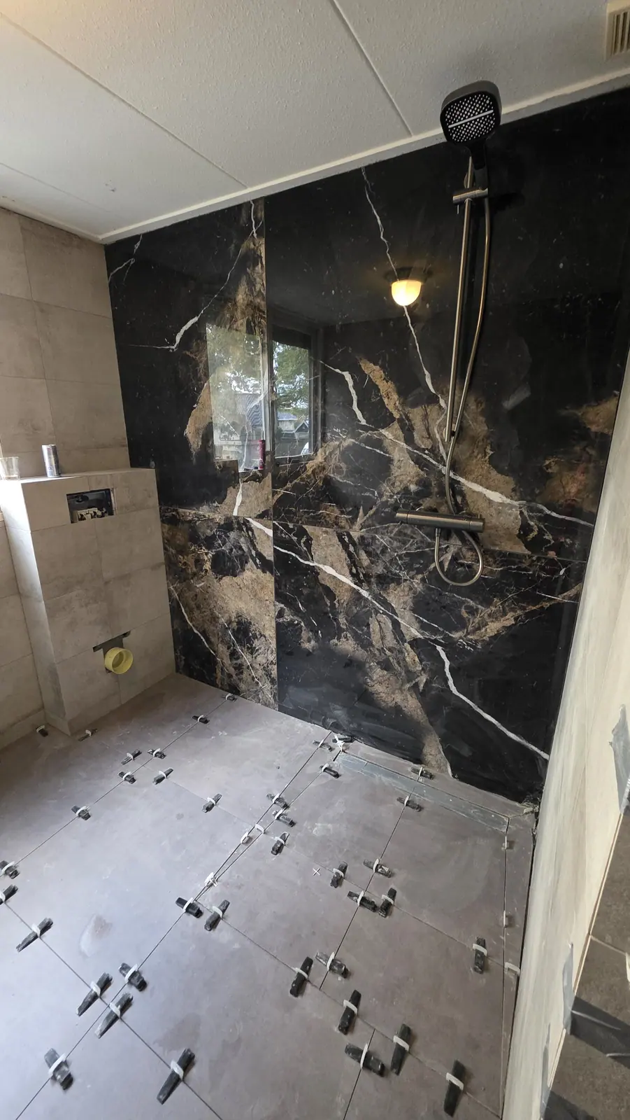 Badkamer met grote tegels van 120 bij 120 centimeter en een marmerlook wand