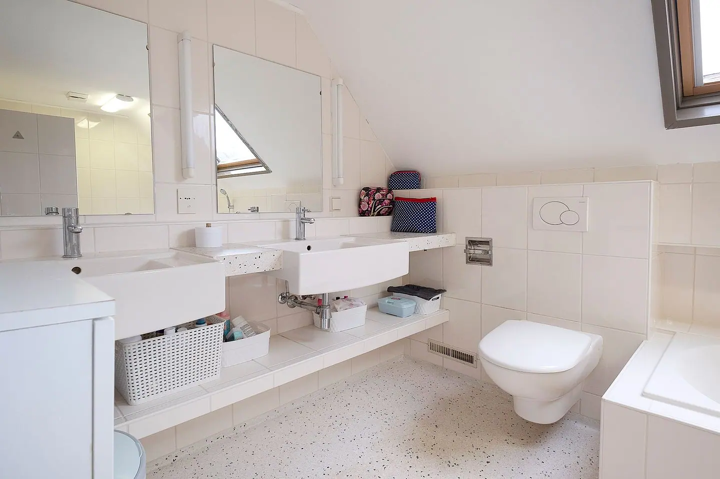 Badkamer onder een schuin dak vóór de verbouwing, met dubbele wastafel, toilet en bad