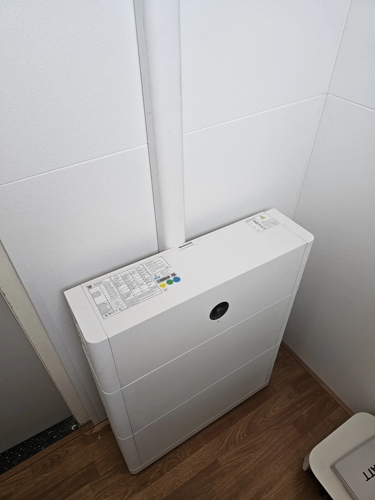 Witte thuisbatterij tegen een wand in een woning